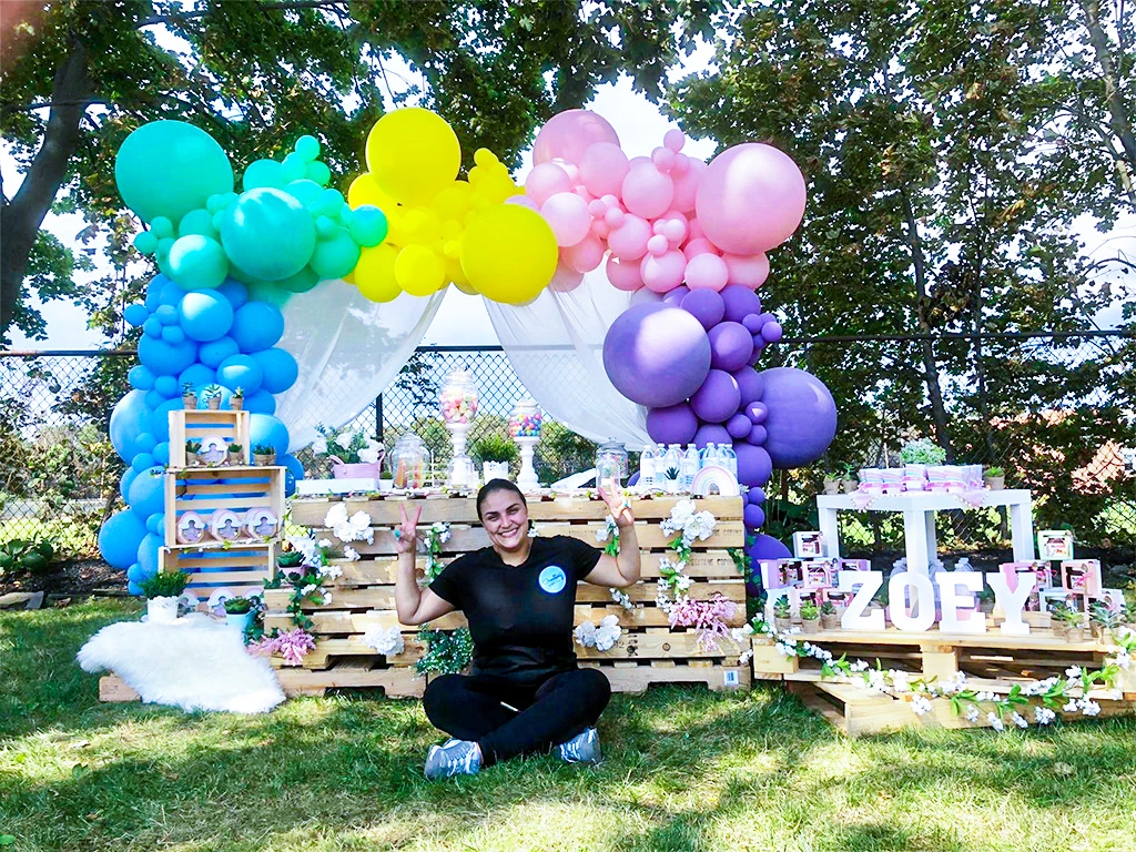 A balloon artist alongside a colorful outdoor balloon installation and styled event display.